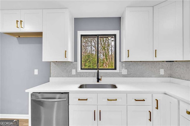 kitchen with dishwasher, backsplash, light countertops, white cabinetry, and a sink