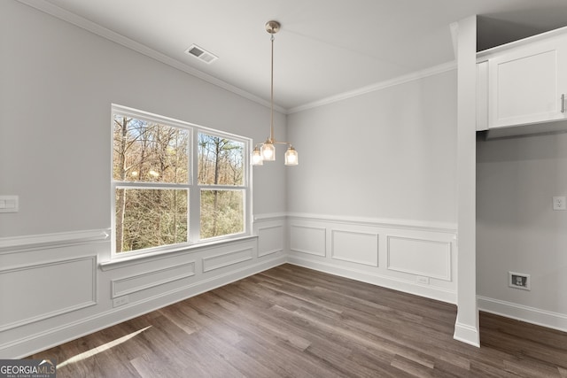 unfurnished dining area featuring a chandelier, a wainscoted wall, visible vents, dark wood-style floors, and crown molding