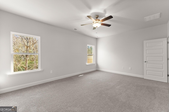 empty room featuring carpet floors, visible vents, baseboards, and a ceiling fan