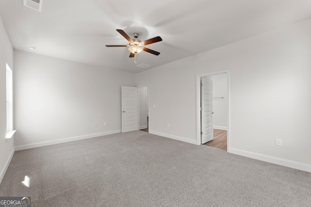 carpeted empty room with visible vents, a ceiling fan, and baseboards