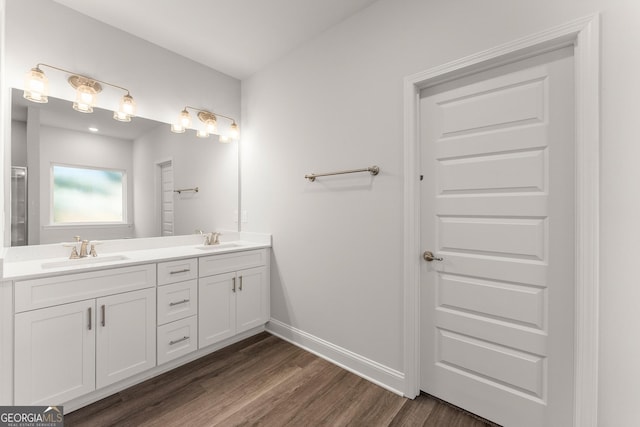 bathroom with double vanity, wood finished floors, a sink, and baseboards