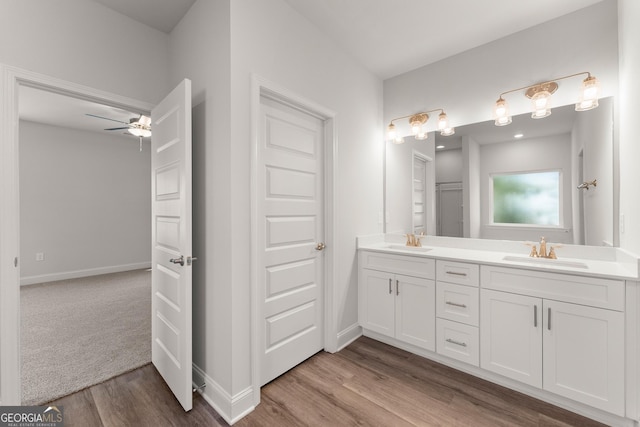 full bath with double vanity, wood finished floors, a sink, and baseboards