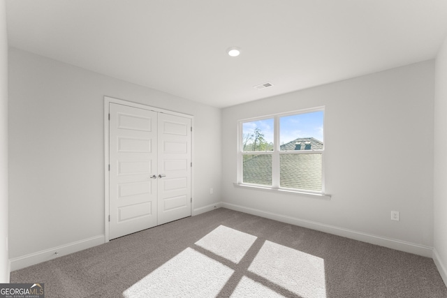 unfurnished bedroom with carpet, visible vents, baseboards, and a closet