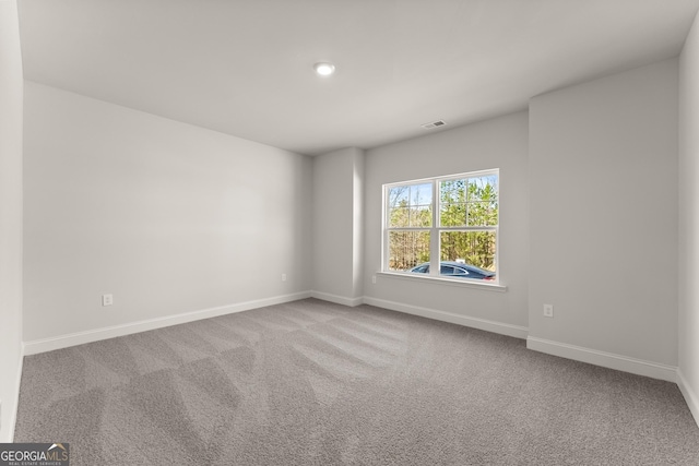 unfurnished room with carpet flooring, visible vents, and baseboards