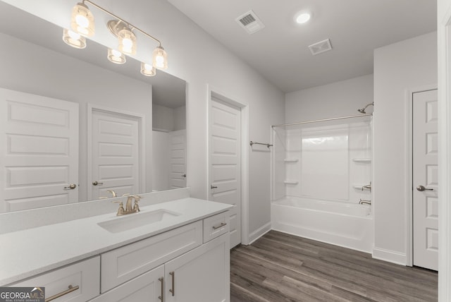 bathroom featuring baseboards, visible vents, wood finished floors, vanity, and shower / bathing tub combination