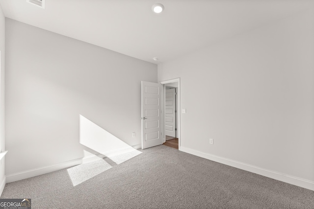 unfurnished room with carpet, visible vents, and baseboards