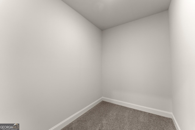 unfurnished room featuring baseboards and dark carpet