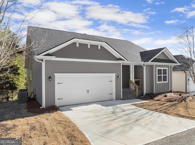 view of front of home featuring a garage, concrete driveway, a shingled roof, and central air condition unit