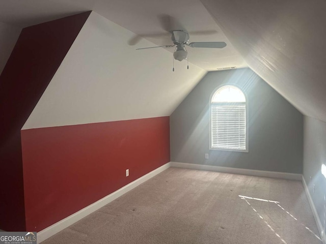 additional living space featuring light carpet, a ceiling fan, visible vents, vaulted ceiling, and baseboards