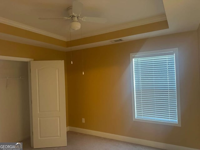 unfurnished bedroom featuring visible vents, baseboards, a closet, a raised ceiling, and crown molding