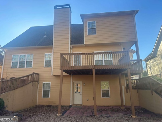 back of property with roof with shingles, a chimney, and stairs