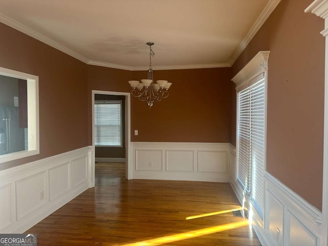 unfurnished dining area with visible vents, wainscoting, wood finished floors, crown molding, and a chandelier