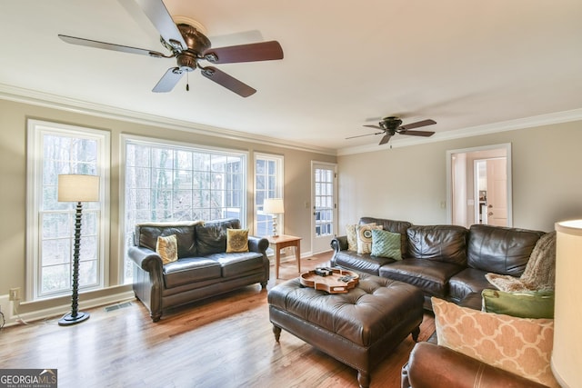 living room featuring a healthy amount of sunlight, ornamental molding, and wood finished floors