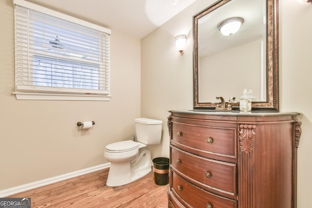 bathroom featuring toilet, baseboards, wood finished floors, and vanity