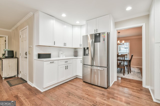 kitchen featuring a notable chandelier, white cabinetry, light wood-style floors, stainless steel fridge, and crown molding