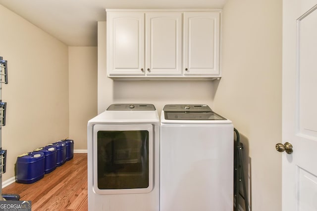 laundry area with cabinet space, baseboards, light wood finished floors, and washing machine and clothes dryer