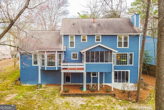 rear view of property featuring a chimney and a sunroom