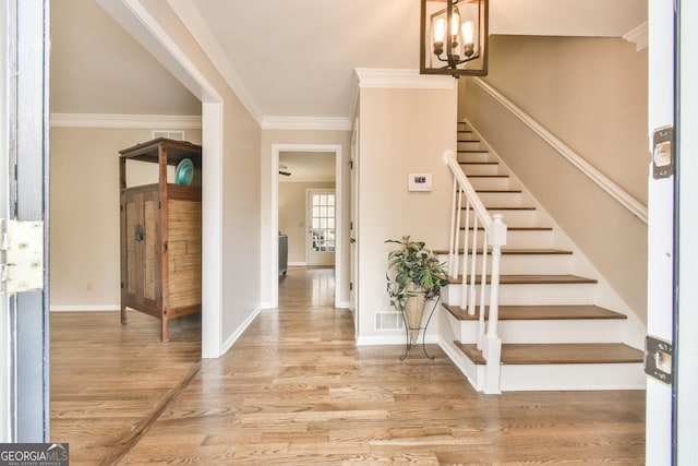 entrance foyer with baseboards, visible vents, wood finished floors, stairs, and crown molding