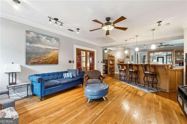 living room with light wood finished floors, a ceiling fan, visible vents, and crown molding