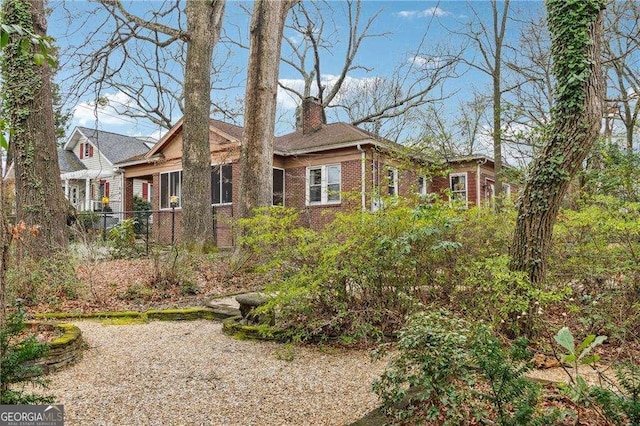 view of front of property with fence, brick siding, and a chimney