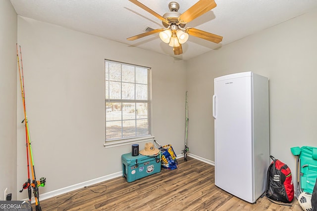 game room with a ceiling fan, a textured ceiling, baseboards, and wood finished floors