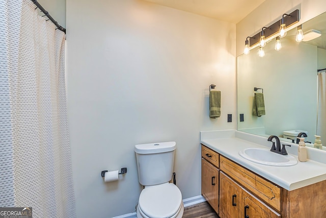 full bath with toilet, baseboards, and vanity