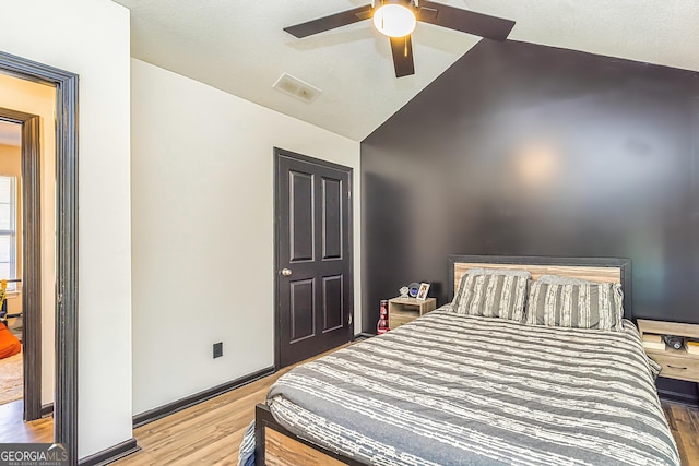 bedroom with lofted ceiling, visible vents, a ceiling fan, wood finished floors, and baseboards