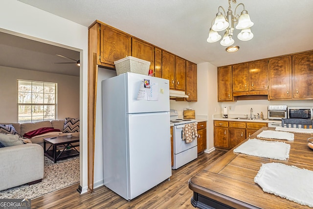 kitchen with white appliances, a sink, open floor plan, light countertops, and decorative light fixtures