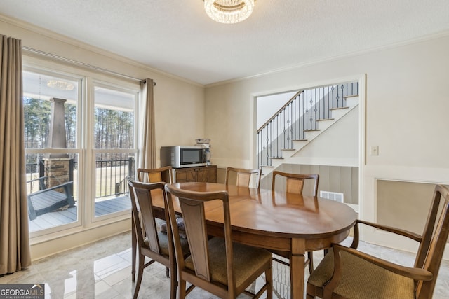 dining room featuring stairs, ornamental molding, a textured ceiling, and visible vents