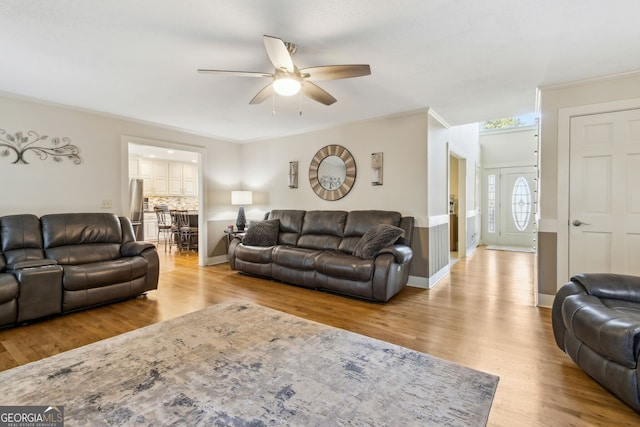 living area featuring baseboards, ornamental molding, and wood finished floors