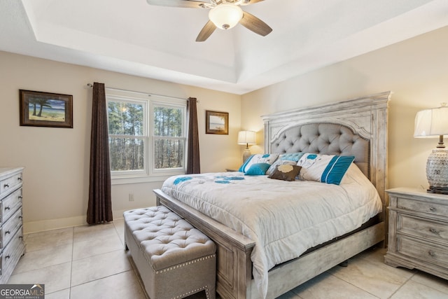 bedroom with light tile patterned floors, ceiling fan, a raised ceiling, and baseboards