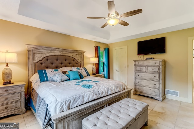 bedroom featuring ceiling fan, light tile patterned flooring, visible vents, baseboards, and a tray ceiling