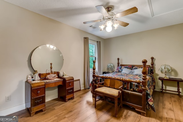 bedroom featuring a ceiling fan, visible vents, baseboards, and wood finished floors