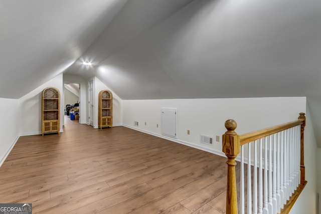 bonus room with lofted ceiling, baseboards, visible vents, and wood finished floors