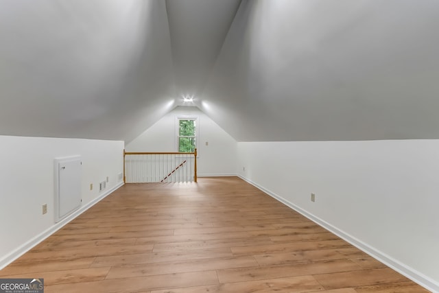 bonus room featuring lofted ceiling, light wood-type flooring, and baseboards