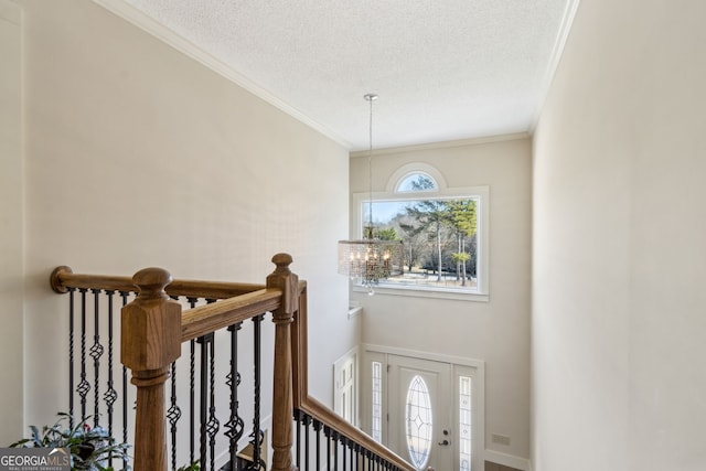 stairs with a notable chandelier, ornamental molding, and a textured ceiling