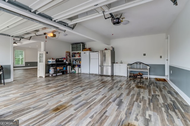 garage featuring baseboards, freestanding refrigerator, and a garage door opener