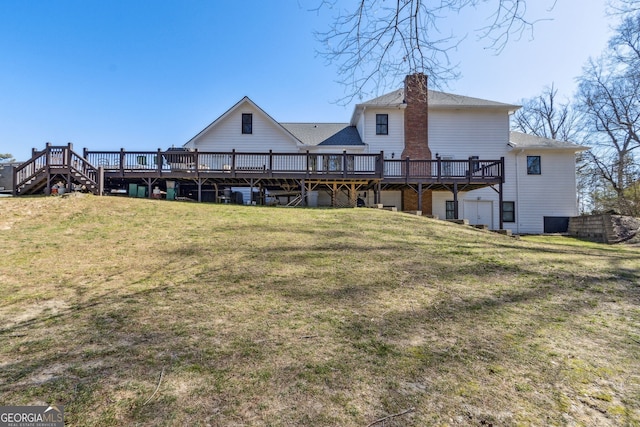 rear view of property with a lawn, a chimney, and a wooden deck