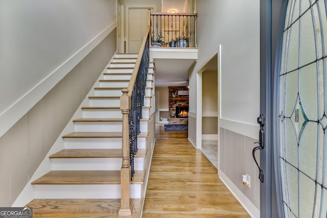 foyer with a high ceiling, stairway, wood finished floors, and a stone fireplace