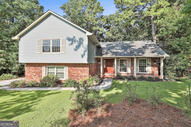 split level home with covered porch, brick siding, and a front lawn