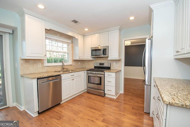 kitchen featuring appliances with stainless steel finishes, a sink, visible vents, and white cabinetry