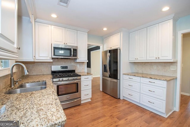 kitchen featuring visible vents, light wood-style flooring, appliances with stainless steel finishes, white cabinetry, and a sink