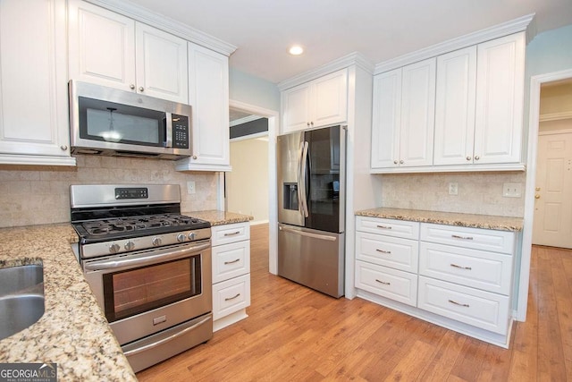 kitchen featuring appliances with stainless steel finishes, light wood-type flooring, white cabinetry, and tasteful backsplash