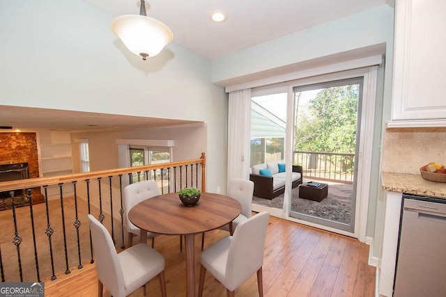 dining space with a fireplace, light wood-style flooring, and recessed lighting