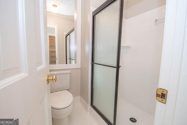 bathroom featuring toilet, a shower stall, and tile patterned flooring