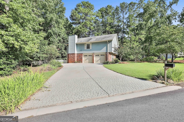 view of front of house with driveway, a garage, brick siding, a chimney, and a front yard