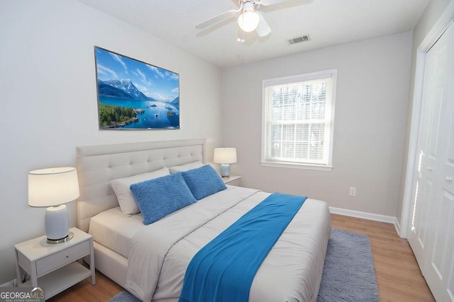 bedroom featuring a ceiling fan, wood finished floors, visible vents, and baseboards