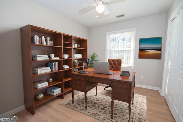 office area featuring light wood-style floors, visible vents, baseboards, and a ceiling fan