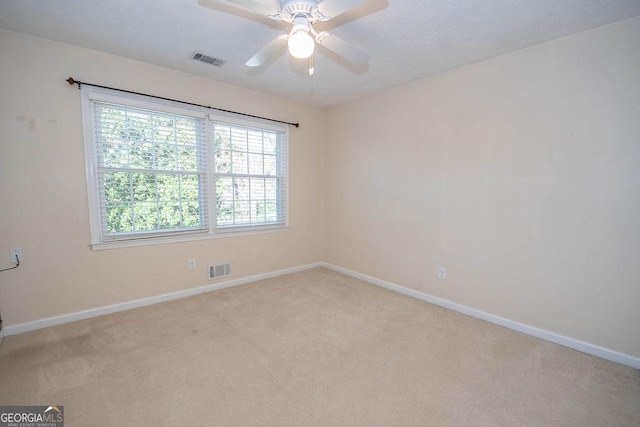 carpeted empty room with visible vents, ceiling fan, and baseboards