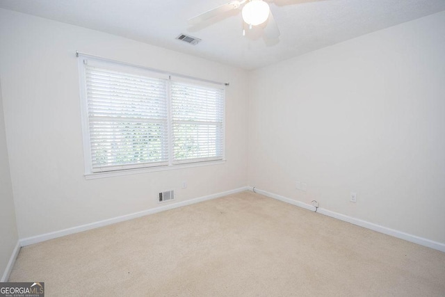 empty room with a ceiling fan, light carpet, visible vents, and baseboards